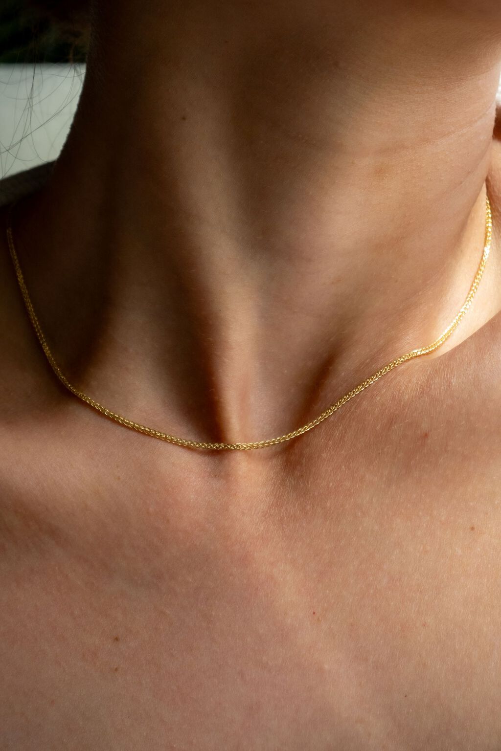 Woman wearing a delicate yellow gold wheat chain